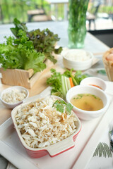 A delicious and visually appealing crab rice dish, served with soup and fresh greens. The dish is presented on a table, with fresh ingredients in the frame