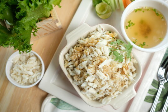 Close-up shot of crabmeat fried rice served with a bowl of soup, rice and vegetable. This shot has a high-angle shot, providing a clear view of the food