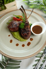 A gourmet meal featuring lamb chops and fresh vegetables artfully arranged on a plate with gravy