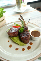 A delicious lamb chop dish, beautifully presented on a plate. The dish looks appetizing with gravy and garnishing