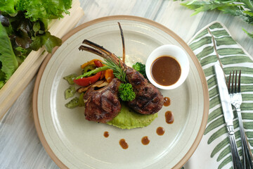 Elegant presentation of a delectable lamb chop dish, garnished with fresh vegetables, and savory gravy