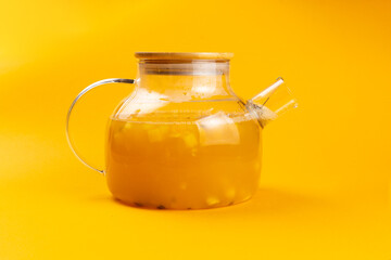 Fruity tea in a teapot on a yellow background.