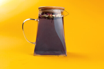 Fruity tea in a teapot on a yellow background.