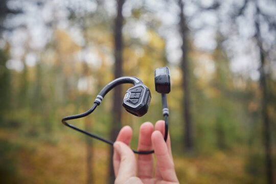 Wireless headphones in a man's hand in the forest