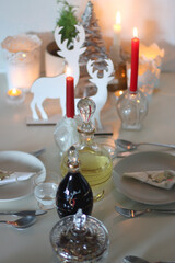 Table set for Christmas meal, with plates, wine, decorations and lit candles. Selective focus.
