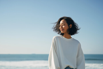 海を背景に髪をなびかせる美しい女性