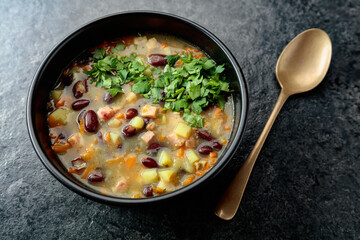 Red bean soup with potatoes, tomatoes, paprika, carrot, and bacon.
