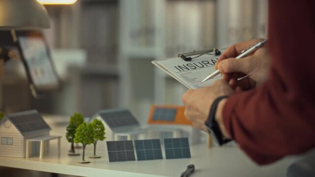 An insurance agent fills out essential documents for a private home featuring solar panels. This detailed work takes place in a contemporary office during daylight hours