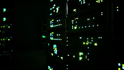 In a dimly lit data center, rows of servers glow with vibrant blue and green lights. This captivating scene showcases the technology and energy of modern computing at work. © icetray