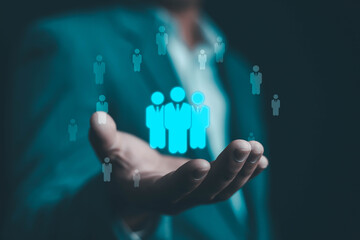 Businessman holding digital human icons representing team management, human resources, and leadership in modern business. Concept of digital HR, recruitment, and workforce organization.