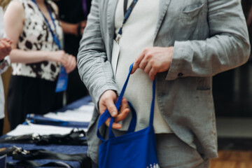 Process of checking in on conference congress forum event, registration desk table, visitors and attendees receiving lanyard with name badge and entry wristband bracelet and register electronic ticket