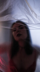 Naklejka premium Woman in a red bra and red lipstick behind cellophane. Erotic mood