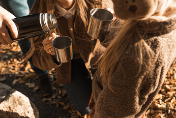 Family on a camping on warm day in fall. Camping, hike and people concept - happy family drink hot tea from thermos.