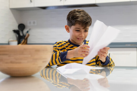Little boy making paper crafts at home kitchen table