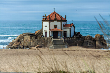 A picturesque white chapel with a red-tiled roof and cross