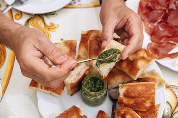 Hand reaching for freshly baked bread with green pesto sauce 
