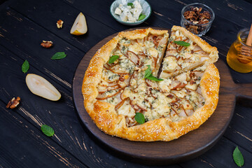 Homemade pear brie galette on wooden board, golden crust, melted cheese, honey glaze. Sliced galette with pear and bri cheese