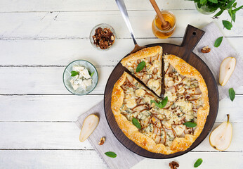 Homemade pear brie galette on wooden board, golden crust, melted cheese, honey glaze. Sliced galette with pear and bri cheese