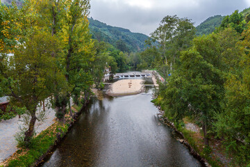 A serene river flows through a lush, tree-lined valley