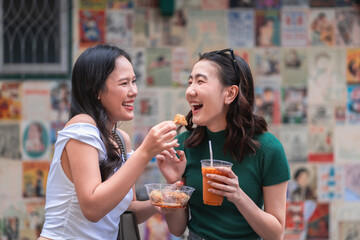 Friends chatting outdoors while holding iced drinks, showing casual social interaction, Asian lifestyle, friendly atmosphere, candid expressions and relaxed urban moments with beverages