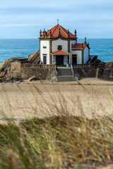 A picturesque white chapel with a red-tiled roof and cross