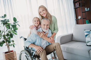 Family together at home a joyful scene with grandfather in wheelchair daughter granddaughter and mom smiling in bright living room