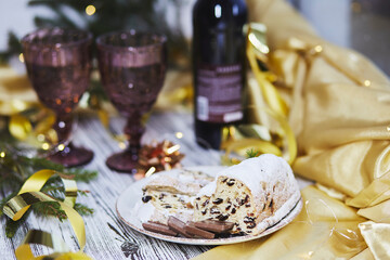 Aesthetic Christmas dinner with bottle of wine and two glasses. Christmas stollen, chocolate and Christmas decorations. Christmas traditions atmosphere background.