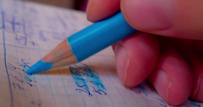 Close-up shot of hand coloring numbers on paper with blue pencil, emphasizing precision and focus in paperwork