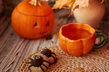 Aesthetics festive Halloween spider cookies with cup of tea in shape of pumpkin. Jack o lantern.