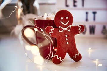 Homemade gingerbread cookie with festive bokeh decor on Let it snow background. Christmas decorations with hot drink and marshmallows. Aesthetic Christmas atmosphere, home coziness, warmth concept