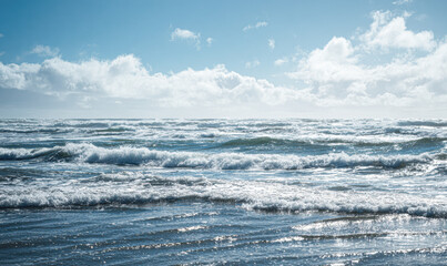 A tranquil ocean scene under a bright blue sky, with gentle waves lapping at the shore, creating a serene and peaceful atmosphere.