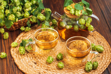 Hop Tea with Fresh Hops in Glass Cups and Teapot on Rustic Background