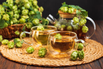 Hop Tea with Fresh Hops in Glass Cups and Teapot on Rustic Background