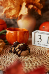 Autumn Halloween cookies in shape of spider and cup of tea in shape of pumpkin near 31 of October on calendar