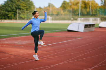 Fototapeta premium Athletic Woman Jumping On Track During Autumn Training On Running Track Field