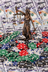 A figure of Themis and casino betting chips against a background of $100 bills.