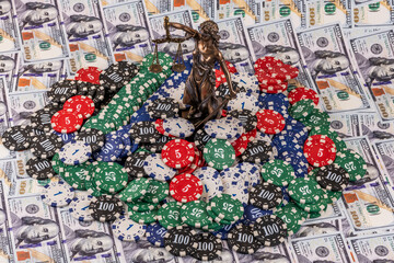 A figure of Themis and casino betting chips against a background of $100 bills.