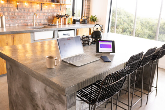 Concrete kitchen island showcasing laptop, tablet, smartphone, mug and window view