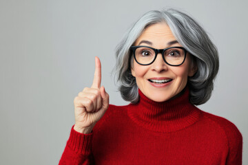 Smiling older woman in red sweater pointing upward with excitement