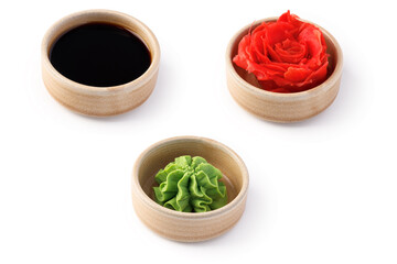 Soy sauce, wasabi and pickled ginger in wooden bowls isolated on white background