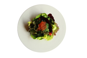 A healthy and delicious salad artfully arranged on a white plate. The salad consists of a variety...