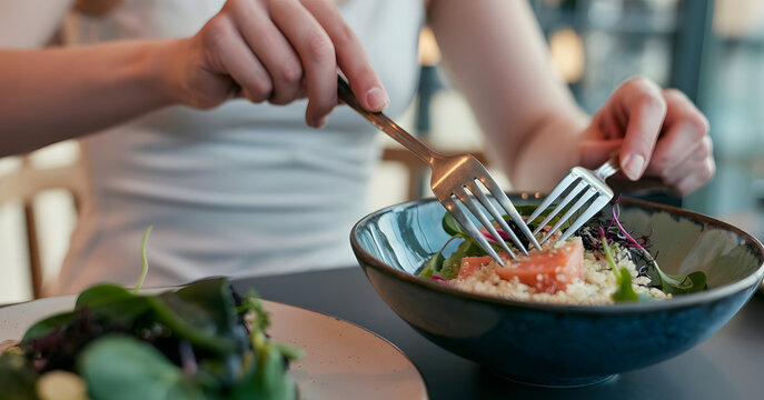 Woman hands eating vegan salad of baked vegetables, avocado, tofu and buckwheat buddha bowl, top view. Plant based food concept