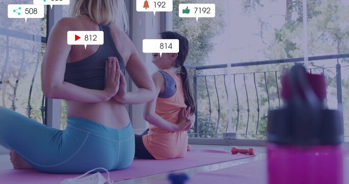 Mother and daughter practicing reverse prayer pose on pink mats on balcony, with social media icons - Powered by Adobe