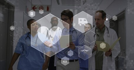 Walking team in scrubs reviewing patient records in hospital corridor, digital interface overlay