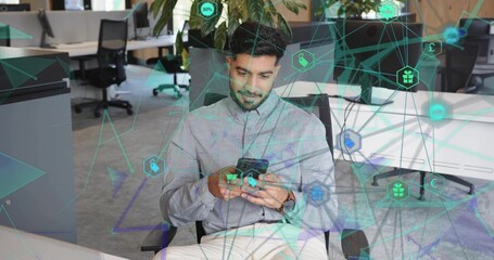 Tapping smartphone screen Indian professional sitting on chair in open-plan office, network overlay © vectorfusionart