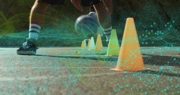 Dribbling male athlete maneuvering soccer ball through orange cones on court, digital overlay