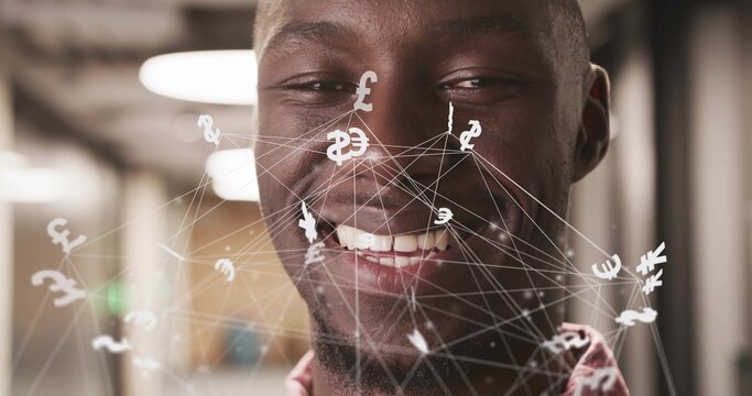 Smiling African American man showing network overlay of currency symbols in office corridor