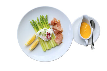 A gourmet dish featuring asparagus, smoked salmon, sauce, and lemon slices arranged on a white plate, showcasing a delightful culinary presentation.
