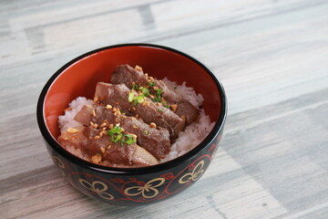 Delicious beef slices served over a bed of fluffy rice in a decorative bowl, ready to eat