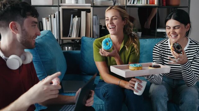 Video of business people eating colorful donuts while taking a break of work in a coworking place